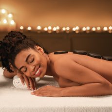 Black young woman getting hot stone massage at spa