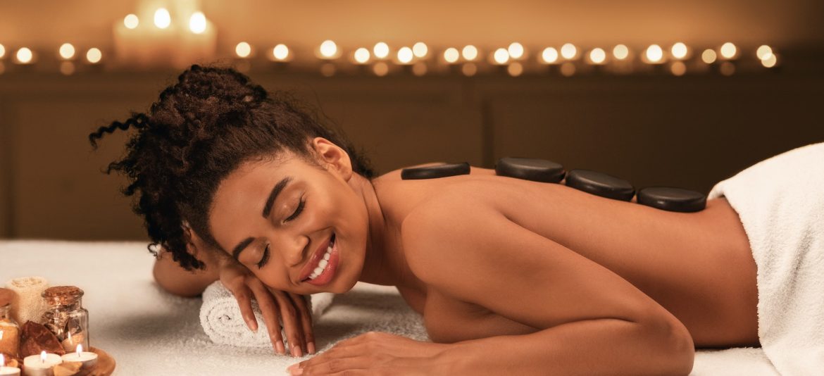 Black young woman getting hot stone massage at spa